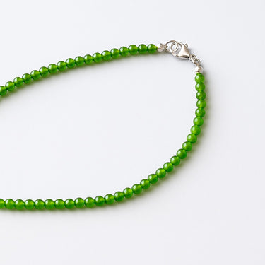 An editorial portrait of a woman wearing the 4mm Jade necklace, emphasizing the piece's structural presence and modern, refined edge.
