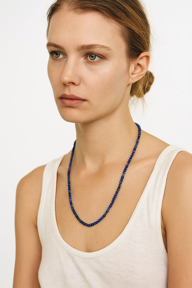 An editorial portrait of a woman wearing the 4mm lapis lazuli necklace, showcasing its sophisticated silhouette and modern, refined edge.
