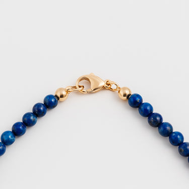A macro detail of 4mm lapis lazuli beads meeting professional-grade 14K gold-filled hardware, featuring a secure lobster clasp.
