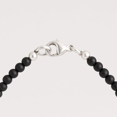 A close-up detail of 4mm matte black onyx beads meeting professional-grade sterling silver hardware, featuring a secure lobster clasp.
