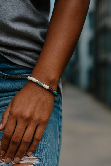 A lifestyle shot of a model wearing a multi-gemstone 4mm heishi bracelet, showcasing the vibrant mix of natural stones and its effortless, stackable silhouette.
