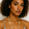 A lifestyle shot of a woman wearing the 4mm multi-stone heishi necklace, showcasing the vibrant colors and clean architectural drape against a white top.
