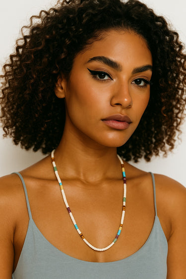 A lifestyle shot of a woman wearing the 4mm multi-stone heishi necklace, showcasing the vibrant colors and clean architectural drape against a white top.
