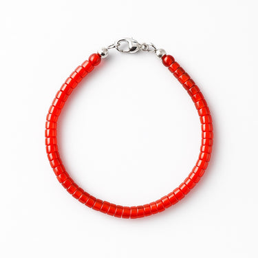 A studio hero shot of a women's 4mm natural red agate heishi bead bracelet with a sterling silver clasp, highlighting the vibrant crimson tones and uniform disk-shaped stones.
