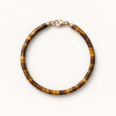 A studio hero shot of a women's 4mm natural tiger's eye heishi bead bracelet with a 14K gold-filled clasp, highlighting the rich golden-brown chatoyancy and uniform disk shape.
