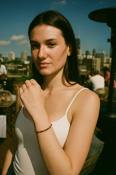 A portrait lifestyle image of a model featuring the 4mm tiger's eye heishi bead bracelet, demonstrating its sophisticated presence and timeless appeal as a modern jewelry staple.
