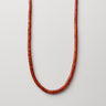 A professional studio hero shot of the women's 4mm red agate heishi necklace arranged in a U-shape against a neutral background, highlighting the uniform disc geometry and vibrant crimson saturation.
