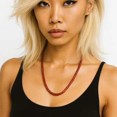 An editorial portrait of a woman wearing the 4mm red agate heishi necklace, emphasizing the piece's structural presence and modern, refined edge.
