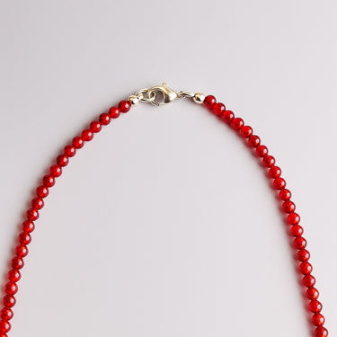 A macro detail view of 4mm red agate beads meeting professional-grade sterling silver hardware, featuring a secure lobster clasp.
