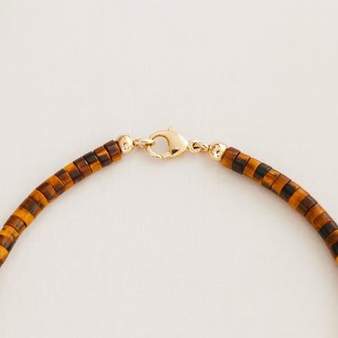 A close-up detail shot of the 4mm Tiger's Eye heishi beads meeting professional-grade 14K gold-filled hardware, emphasizing the modern, refined edge and secure lobster clasp.
