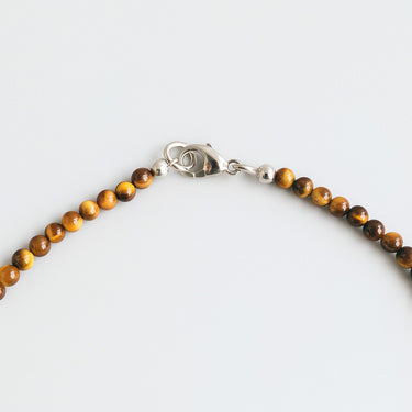 A macro close-up of the professional-grade sterling silver lobster clasp closure on the 4mm Tiger’s Eye round bead necklace.
