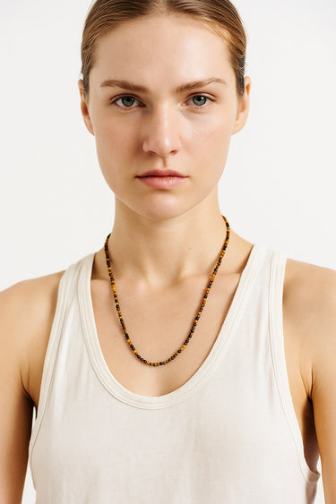 A centered lifestyle portrait of a model wearing the 4mm Tiger’s Eye necklace, demonstrating its sophisticated presence and modern luxury aesthetic.
