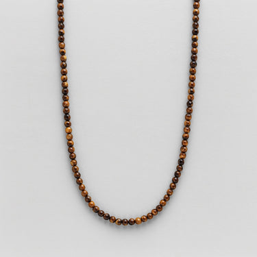 A 4mm Tiger’s Eye round bead necklace arranged in a clean U-shape against a neutral background, highlighting the consistent size and rich golden-brown banded texture.
