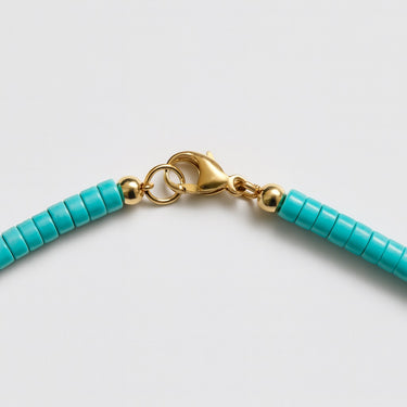 A detailed close-up of a 14K gold-filled lobster clasp closure on the 4mm Blue Turquoise heishi necklace.
