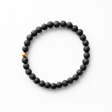A studio hero shot of a women's 6mm black lava bead bracelet featuring a single 14K gold-filled accent bead, highlighting the porous volcanic texture and architectural contrast.
