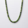 A studio shot of the women's 6mm chrome diopside round bead necklace curved in a U-shape against a neutral background, highlighting the uniform scale and rich emerald saturation.
