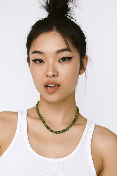An editorial portrait of a woman wearing the 6mm chrome diopside necklace, emphasizing its refined, structural presence and vibrant green tonality.
