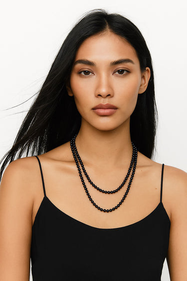An editorial portrait of a woman wearing the 6mm gloss onyx necklace, emphasizing the piece's structural presence and modern, refined edge.
