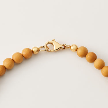 A macro close-up of the professional-grade 14K gold-filled lobster clasp closure on the 6mm Golden Sandalwood round bead necklace.
