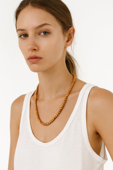 A portrait-view lifestyle shot of a model wearing the 6mm Golden Sandalwood necklace, demonstrating its refined presence and modern luxury aesthetic.
