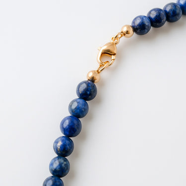 A macro close-up of the professional-grade 14K gold-filled lobster clasp closure on the 6mm Lapis Lazuli round bead necklace.
