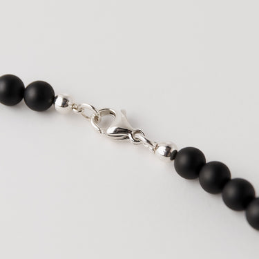 A macro close-up of the professional-grade sterling silver lobster clasp closure on the 6mm Matte Black Onyx necklace.

