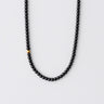 A 6mm Matte Black Onyx round bead necklace featuring a single 14K gold-filled accent bead, arranged in a clean U-shape against a neutral background.
