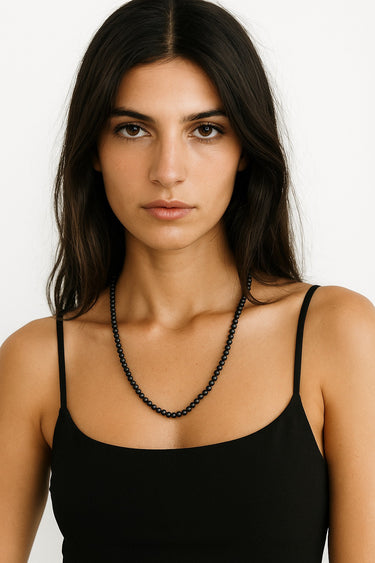 A centered lifestyle portrait of a model wearing the 6mm Matte Black Onyx necklace, demonstrating its sophisticated presence and refined modern luxury.
