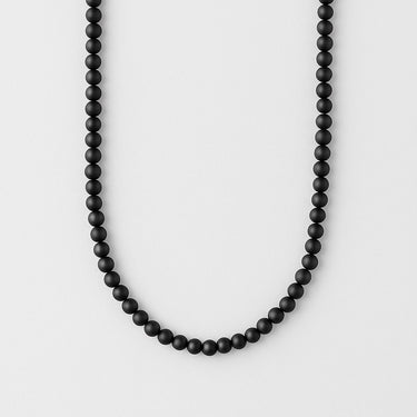 A 6mm Matte Black Onyx round bead necklace arranged in a clean U-shape against a neutral background, showcasing the consistent matte finish and deep obsidian tone.
