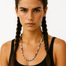A lifestyle shot of a woman wearing the 6mm handmade Millefiori glass necklace, showcasing the vibrant multi-colored floral patterns and clean architectural drape against a black top.
