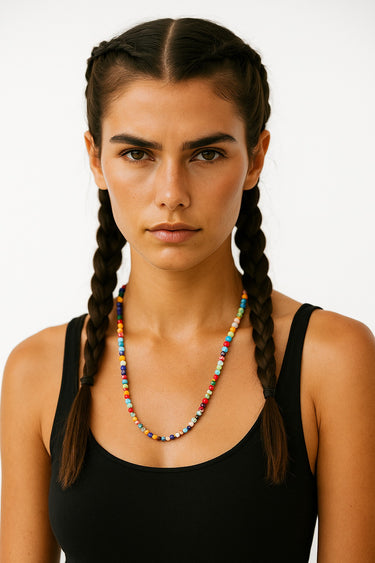 A lifestyle shot of a woman wearing the 6mm handmade Millefiori glass necklace, showcasing the vibrant multi-colored floral patterns and clean architectural drape against a black top.
