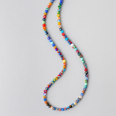 A studio shot of the 6mm Millefiori necklace in a fluid S-curve, highlighting the unique patterns within each handmade glass bead.


