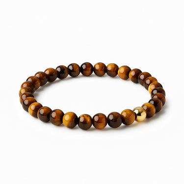 An angled studio shot of the 6mm Tiger's Eye bead bracelet with a gold-filled accent, emphasizing the uniform bead size and the architectural quality of the minimalist design.
