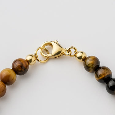A macro close-up focusing on the professional-grade 14K gold-filled lobster clasp and gold accent beads on the 6mm Tiger’s Eye necklace.
