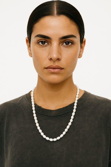 A woman wearing a longer strand variation of the 7-8mm freshwater pearl necklace, showcasing its fluid drape and sophisticated editorial silhouette.
