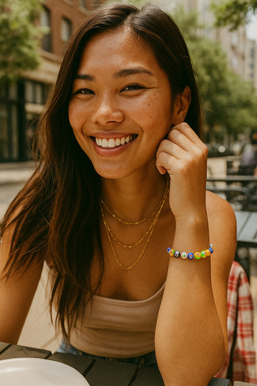 A portrait lifestyle shot of a model wearing the 8mm Millefiori glass bead bracelet, demonstrating its playful yet sophisticated presence as a modern staple piece for casual styling.
