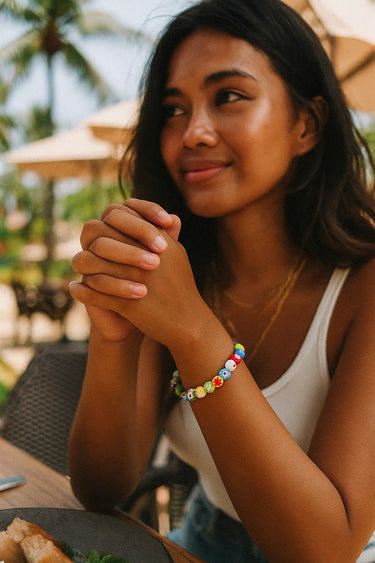A lifestyle portrait of a model wearing a multi-colored 8mm Millefiori glass bead bracelet, demonstrating its playful yet sophisticated aesthetic and versatile styling potential.
