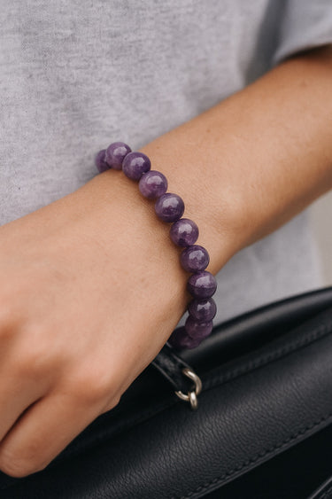 A close-up lifestyle image of the 8mm amethyst bead bracelet on a model’s wrist, emphasizing the uniform round stones and the effortless drape of this handcrafted staple piece.
