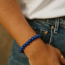 A lifestyle shot of a model wearing the 8mm blue lapis lazuli bead bracelet, demonstrating its vibrant color and effortless, stackable silhouette against casual denim.
