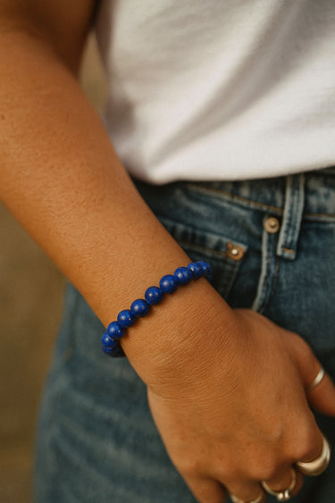 A lifestyle shot of a model wearing the 8mm blue lapis lazuli bead bracelet, demonstrating its vibrant color and effortless, stackable silhouette against casual denim.
