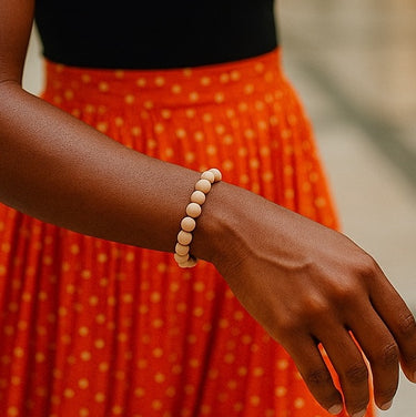 A lifestyle shot of a model wearing an 8mm fossil jasper bead bracelet against a vibrant orange skirt, showcasing its neutral, organic palette and effortless handcrafted quality.
