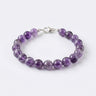 A studio product shot of a women's 8mm natural amethyst bead bracelet with a sterling silver lobster clasp.