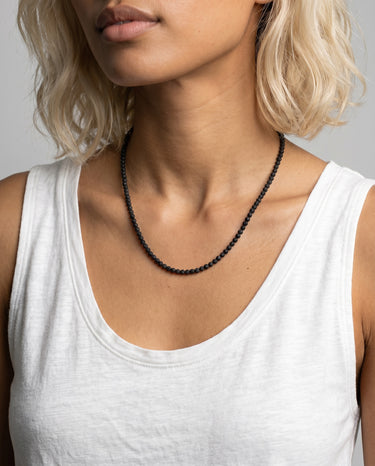 woman with a white tank top wearing 4mm black lava heishi beaded necklace against a plain background