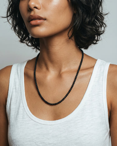woman with a white tank top wearing 4mm black matte onyx beaded necklace against a plain background