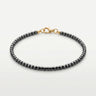 A studio product shot of a women's AAA natural black tourmaline  faceted 2mm cube beads bracelet with 14k gold-filled lobster clasp.