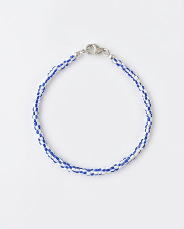 A studio product shot of a women's 2-3mm blue and white african chevron bead bracelet with a sterling silver lobster clasp on a white background.