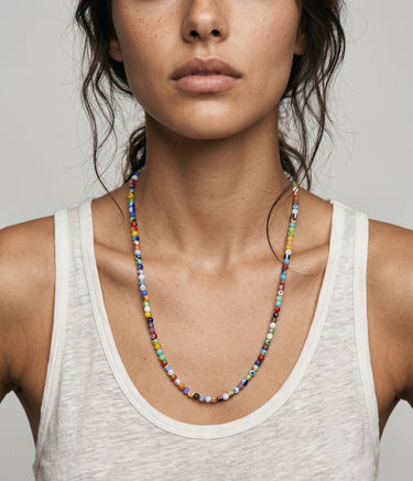 Colorful 4mm round millifiori beaded necklace worn by a woman in a white tank top against a neutral background