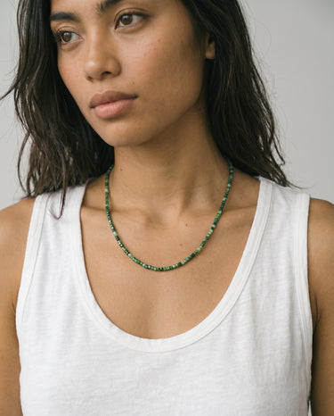 Woman wearing a faceted tourmaline beaded necklace against a neutral background
