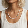 Close-up of a freshwater pearl necklace worn by a woman, featuring lustrous white freshwater pearls and a short stack of green Aventurine heishi disc beads positioned off-center.