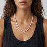 Woman wearing a pearl necklace against a neutral background
